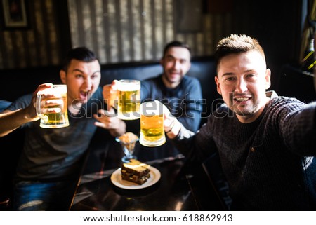 people, leisure, friendship, technology and party concept - happy male friends taking selfie and drinking beer at bar or pub