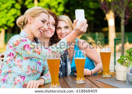 Friends taking selfie with smartphone in beer garden