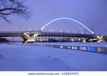 Snow Drifts Along the Frozen Mississippi River Under the Blue Lowry Avenue Bridge in front of Minneapolis Skyscrapers on a Gloomy Winter Twilight 