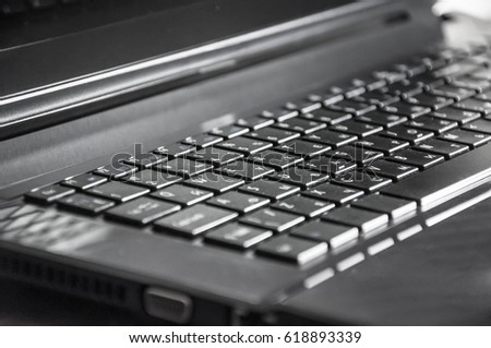 A closeup of a grey plastic notebook keyboard with a part of a screen and with focus on the left side keys
