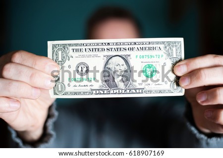 A man holds a U.S. 1 one dollar. Royalty-Free Stock Photo #618907169