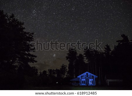 Night starry sky scene with illuminated cottage