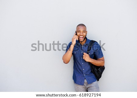 Portrait of young african man laughing with mobile phone against gray wall