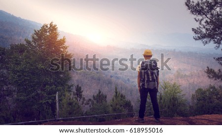 Young male with backpack enjoying sunset on mountain. Hiker looking sunlight in trip in South Asia.