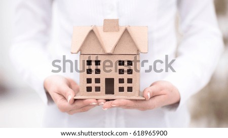 Woman is holding an architectural model of a house