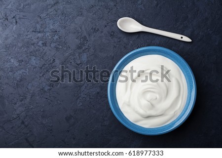 Greek yogurt in blue bowl on black table top view. Royalty-Free Stock Photo #618977333