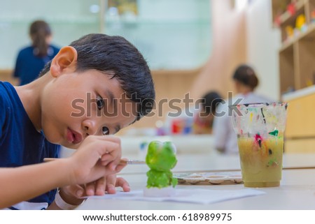 image of young asian boy painting a doll with water color.