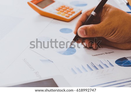 Business meeting, man's hands pointing on charts. Reflection light and flare. Concept image of data gathering and statistical working.
