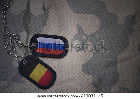 army blank, dog tag with flag of russia and belgium on the khaki texture background. military concept