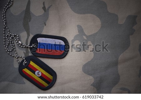 army blank, dog tag with flag of russia and uganda on the khaki texture background. military concept