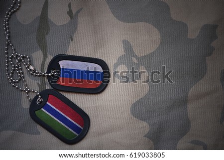 army blank, dog tag with flag of russia and gambia on the khaki texture background. military concept