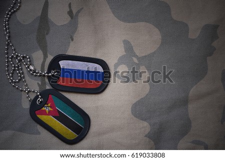 army blank, dog tag with flag of russia and mozambique on the khaki texture background. military concept