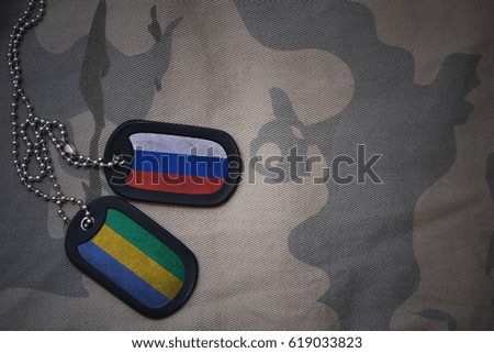 army blank, dog tag with flag of russia and gabon on the khaki texture background. military concept
