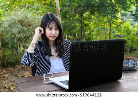 Beautiful tan skin Asian business chic woman hand typing laptop computer keyboard and phone working email with internet communication in forest. Presenting your product in coffee shop.