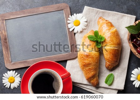 Blackboard for your text, croissants, berries, flowers and coffee cup. Top view with copy space