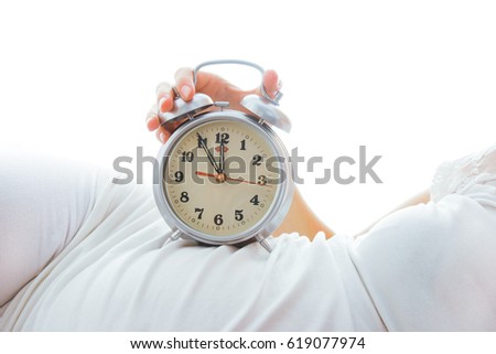 beautiful young pregnant girl on a white background with alarm clock