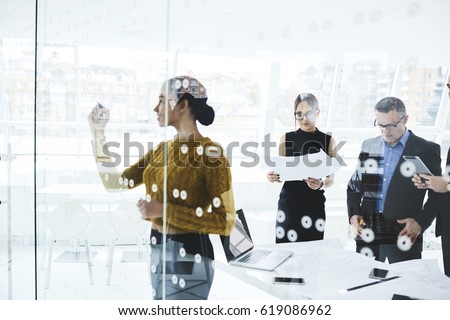 Young skilled afro american elegant dressed female secretary writing on board plan for workshop while professional journalists reading press release of official event in modern conference room Royalty-Free Stock Photo #619086962