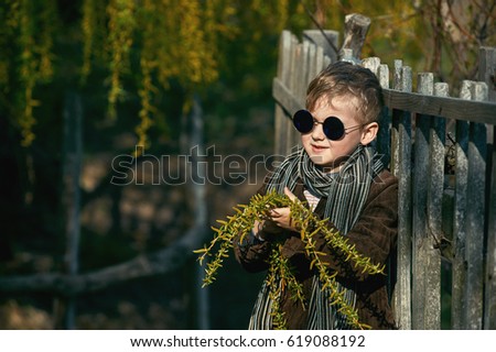 Stylish retro portrait of a boy in the countryside . The boy holds in his hands the flowering branches