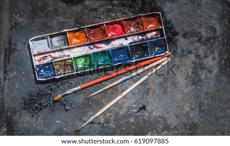 Old used watercolor set and old brushes on grunge metal background. With space for text