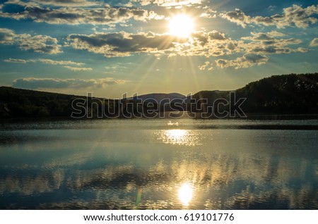 sun shining in the sky above calm blue lake