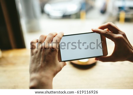 Photos of food on a smartphone for social networks. A girl is sitting in a restaurant and taking pictures of her tea.