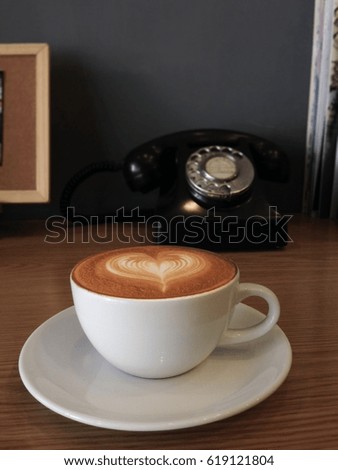 Hot cappuccino white coffee cup on wooden table with vintage telephone background