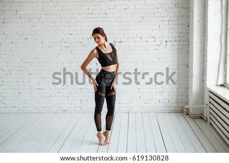 Young happy beautiful woman practicing yoga, wearing track suits, black suit, white loft Studio backdrop Royalty-Free Stock Photo #619130828