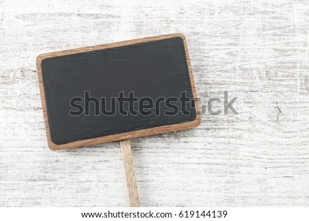 Blank blackboard label isolated on a white wooden background, copy space.