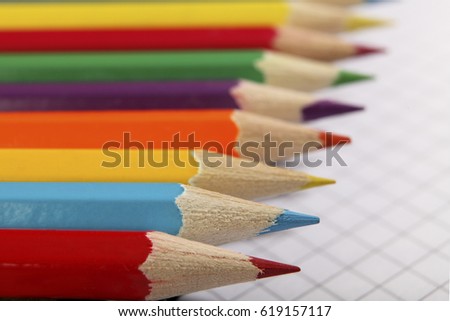 Color pencils lie hardly on the sheet of a school notebook. Selective focus