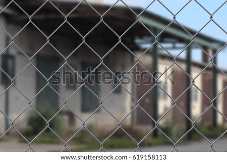 Close up of a wire fence with a blurred industrial area in the background  - safety concept