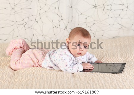 A six-month baby with a tablet computer, looking at screen, at home 