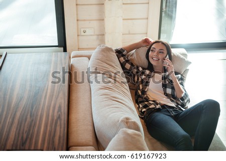 Pretty woman lying on soft couch and talking on phone