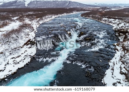 Aerial view of beautiful Bruarfoss waterfall with turquoise water and snow in winter, South Iceland