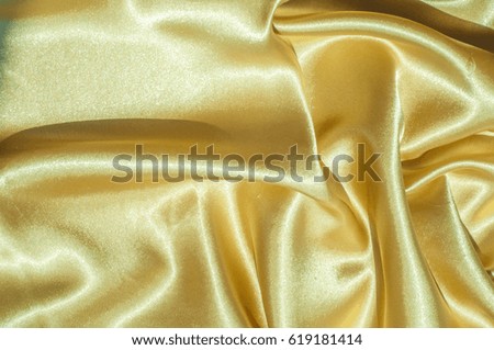 Texture, fabric, background. Abstract background of luxurious fabric or liquid waves or wavy grunge crease silk satin texture of velvet material or luxurious Christmas or elegant background. gold