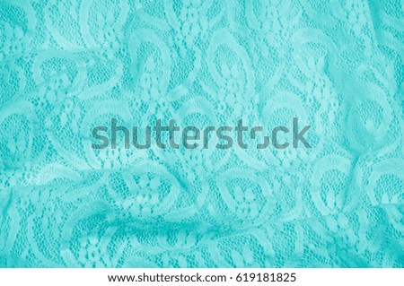 Texture, fabric, background. Lacy turquoise fabric, lace. A thin open fabric, usually cotton or silk, made by a loop, twisting or knitting on patterns and is used specially for trimming clothes.
