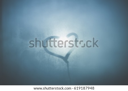Love and sign, valentine's day heart shape written on a foggy window background