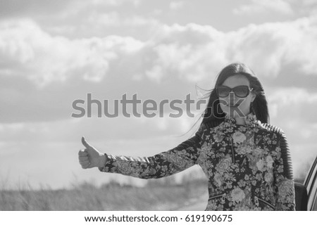 black and white, girl stops the car, holding up a hand.