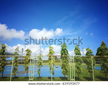 Beatiful blue sky on the basketball sport field with tree fence background in summer in thailand