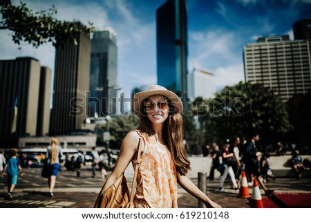 Smiling face woman in hat and sunglasses exploring the city, with Sydney skyline in the background.