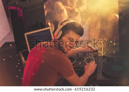 Happy dj playing music on mixer with vinyl record Royalty-Free Stock Photo #619216232