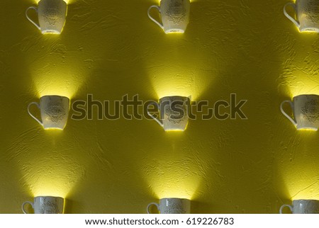 Yellow wall with lamps in the form of mugs