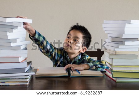Asian kid handle stack of the books, pencil and notebook on the wooden table