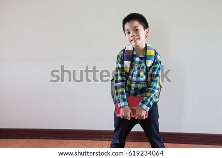 Happy asian kid holding book and shoulder bag
