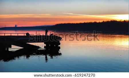 Sunset at the old pier. Landscape the bright colors of the sky over the water. Relaxing idyllic scene.