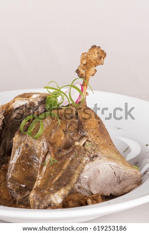 Traditional dish with baked drumstick duck and sour cabbage, decorated with herbs, placed on white plate, light background, isolated