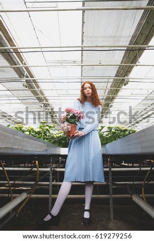 Full-length shot of interesting girl with pink plant in hands
