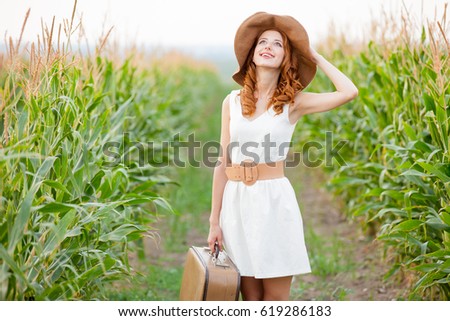 photo of beautiful young woman with suitcase on the wonderful field background