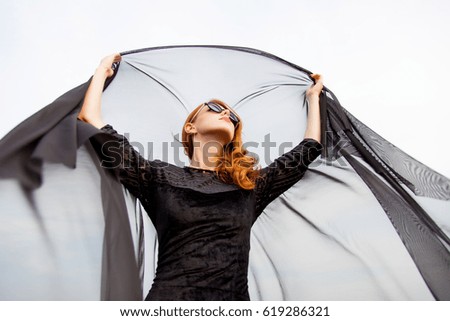photo of beautiful young woman holding shawl on the wonderful  sky background