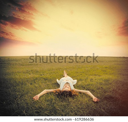 photo of beautiful young woman lying in the field on the sky background