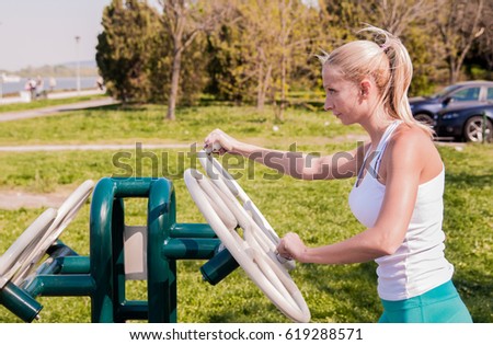 Young female athlete exercising on exercise machine outdoors. woman working out in gym. woman exercising with exercise equipment in the public park